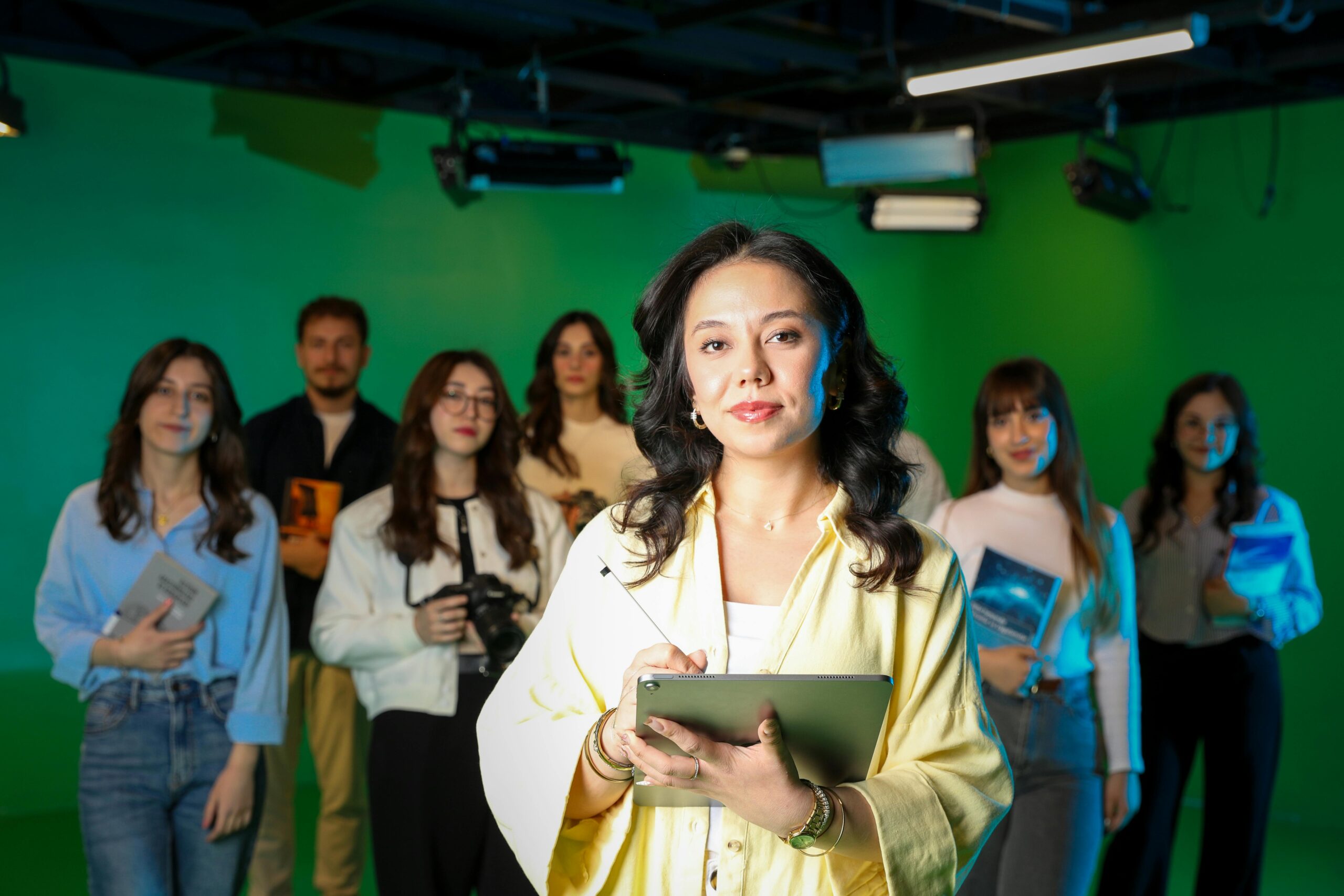 A diverse group of professionals working collaboratively in a green screen studio setting.